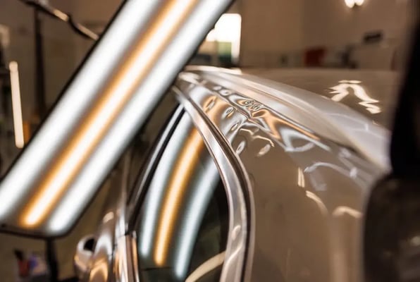 Light reveals paintless dent removal on car rail