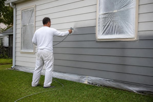 Exterior painting in progress with sprayer